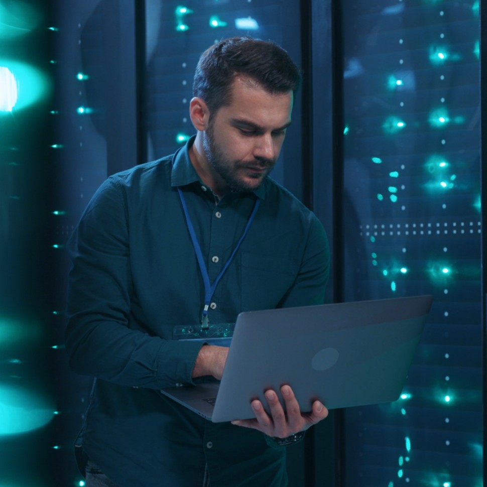 Cybersecurity Services from TBS, image of man on laptop next to servers